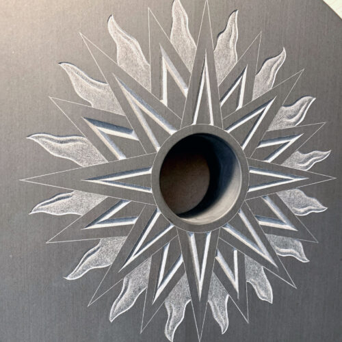 Detail shot of a fire-star carved in relief on a black slate.