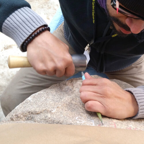 Downshift of the artist Javier R. Alfonzo carving a large granite boulder.