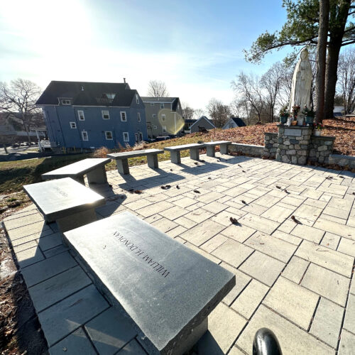 Image shows granite benches set around a monumento of a Virgin Mary with benefactor names carved into them. Westwood, MA
