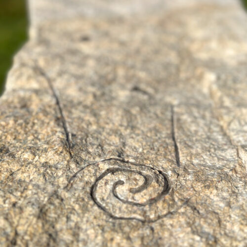 Detail of a spiral comet carved on a granite bench.