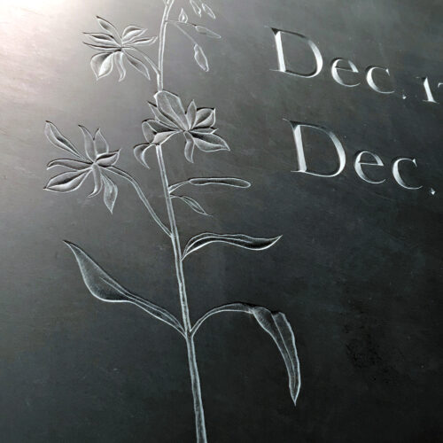 Details of wild flowers relief carving on black slate.