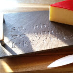 An image of a purple slate cheese tray with a waxed covered chunk of gouda cheese and the inscription "So.. do you like cheese?